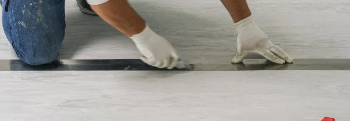 Person verlegt Vinylboden mit Spachtel